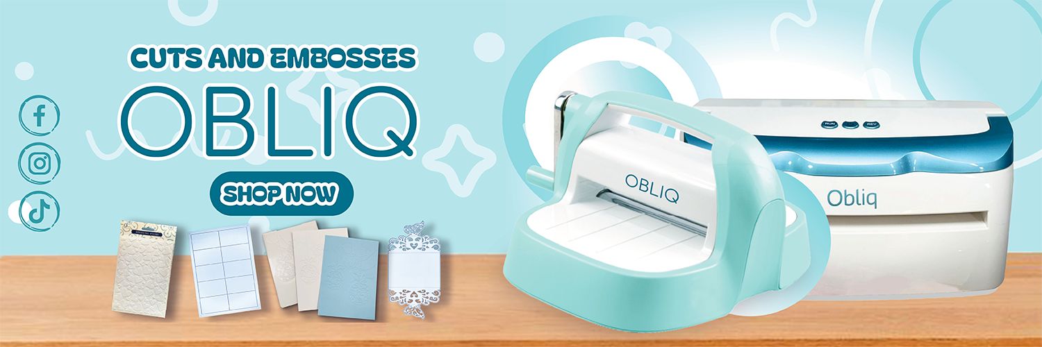 Obliq cutting and embossing machine with accessories on a wooden surface against a light blue background.